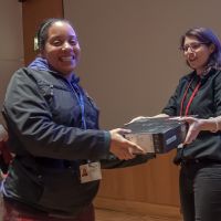 WCM staff member giving another wcm staff member a laptop as a raffle gift