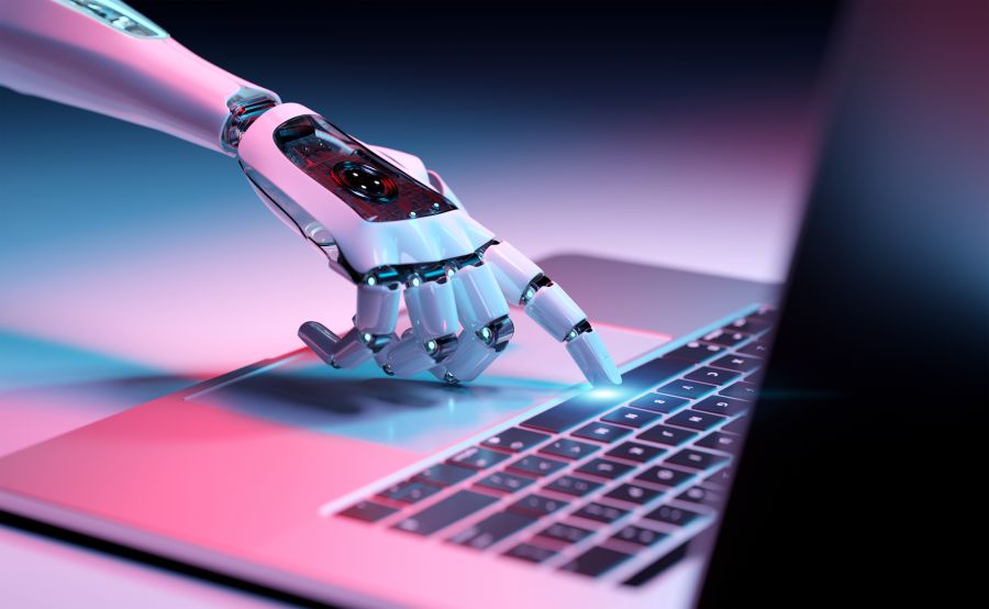 A robot hand touching a laptop keyboard.