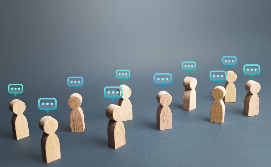 Several small wooden block people with talking bubbles above their heads