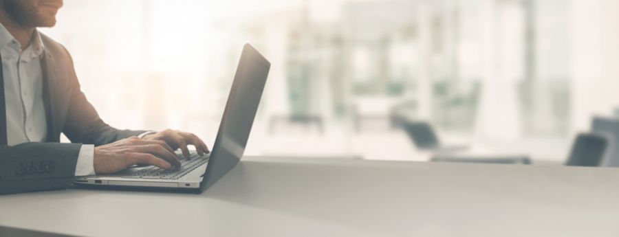 Man in a suit typing on a laptop keyboard