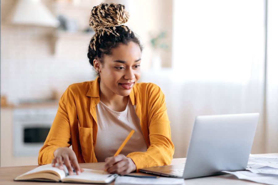 Woman taking an online course on her laptop and taking notes