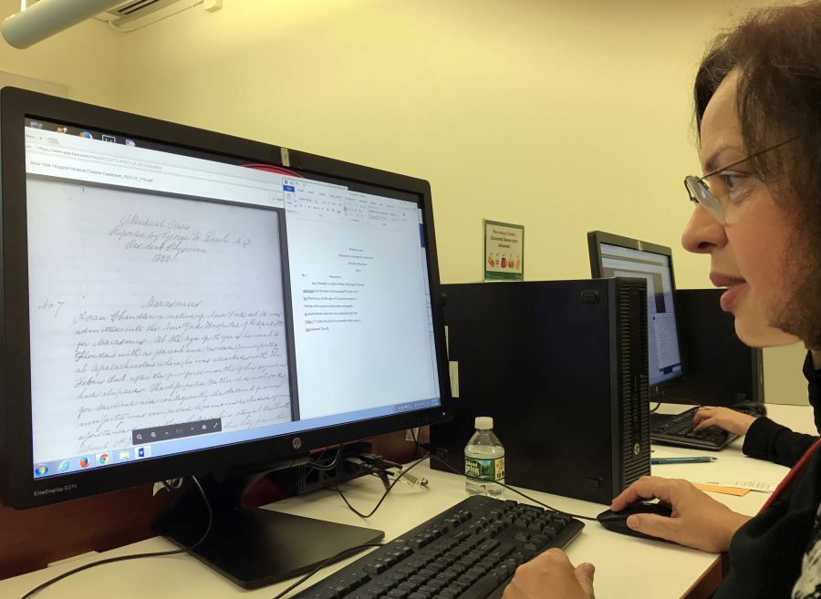 Woman sitting in front of a computer looking at a flat screen monitor