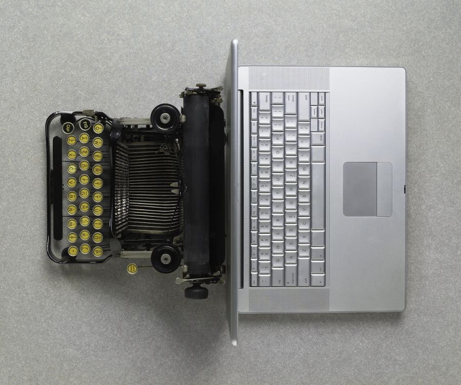 Top View of a vintage typewriter back to back with a modern laptop computer