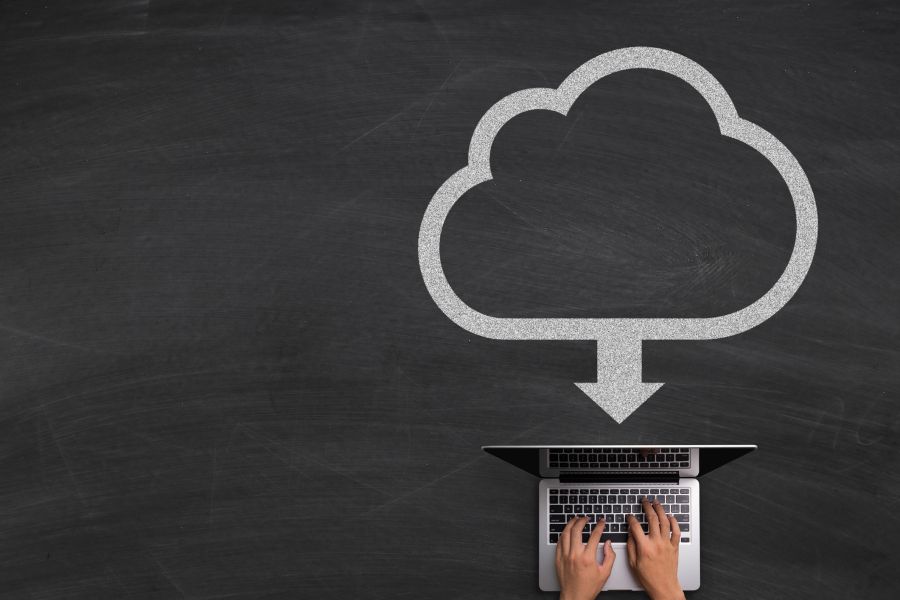 A large cloud icon pointing to a laptop that a person is using.