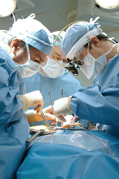 Surgeons performing surgery on a patient in an operating room.
