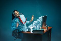 Man being bombarded with mail spilling out of his computer screen.