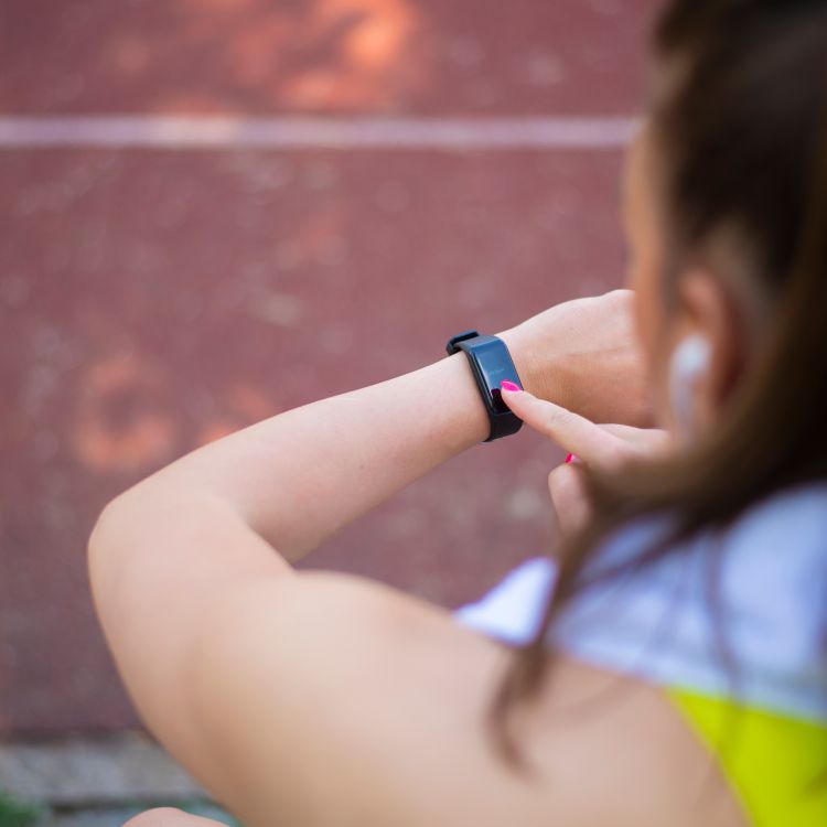 Woman tapping the touchscreen of a health wearable on her wrist.
