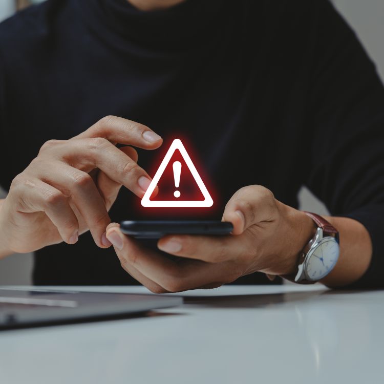 A person using a smartphone with a warning icon flashing above it.