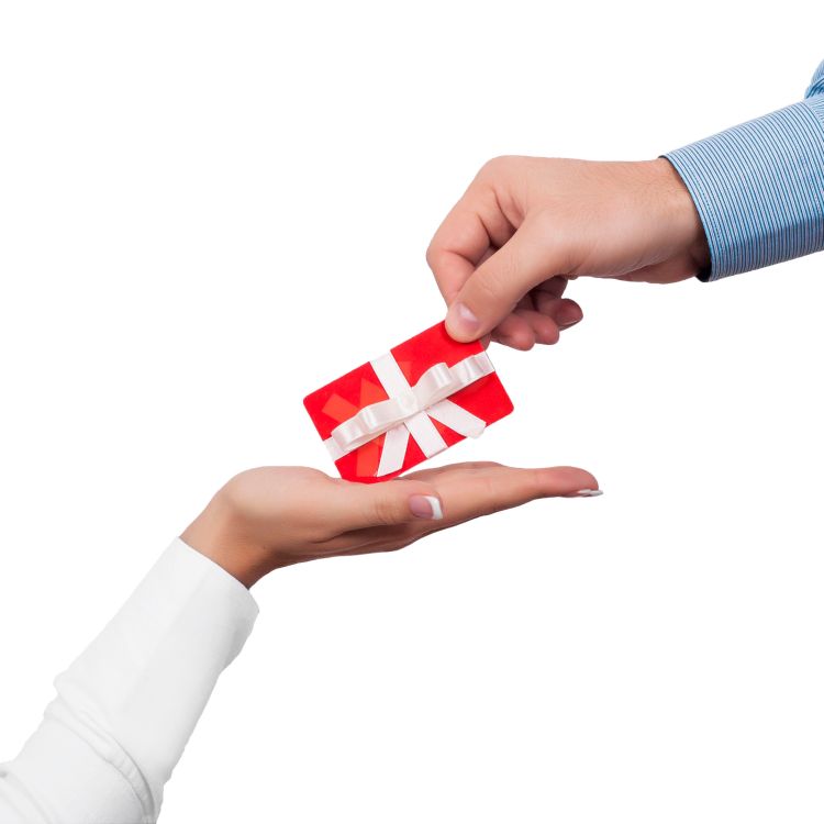 Person's hand offering gift card to another person's hand